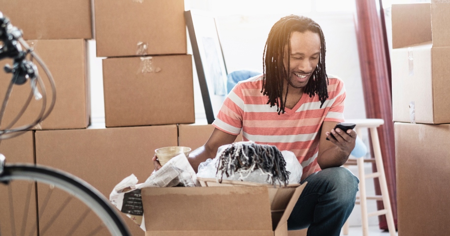 Man packing boxes and smiling at phone