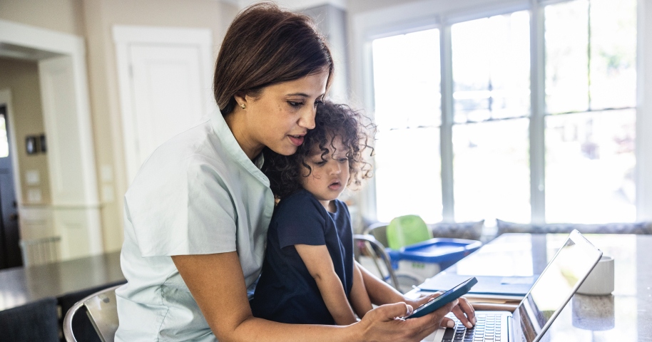 Woman checking phone with child in lap