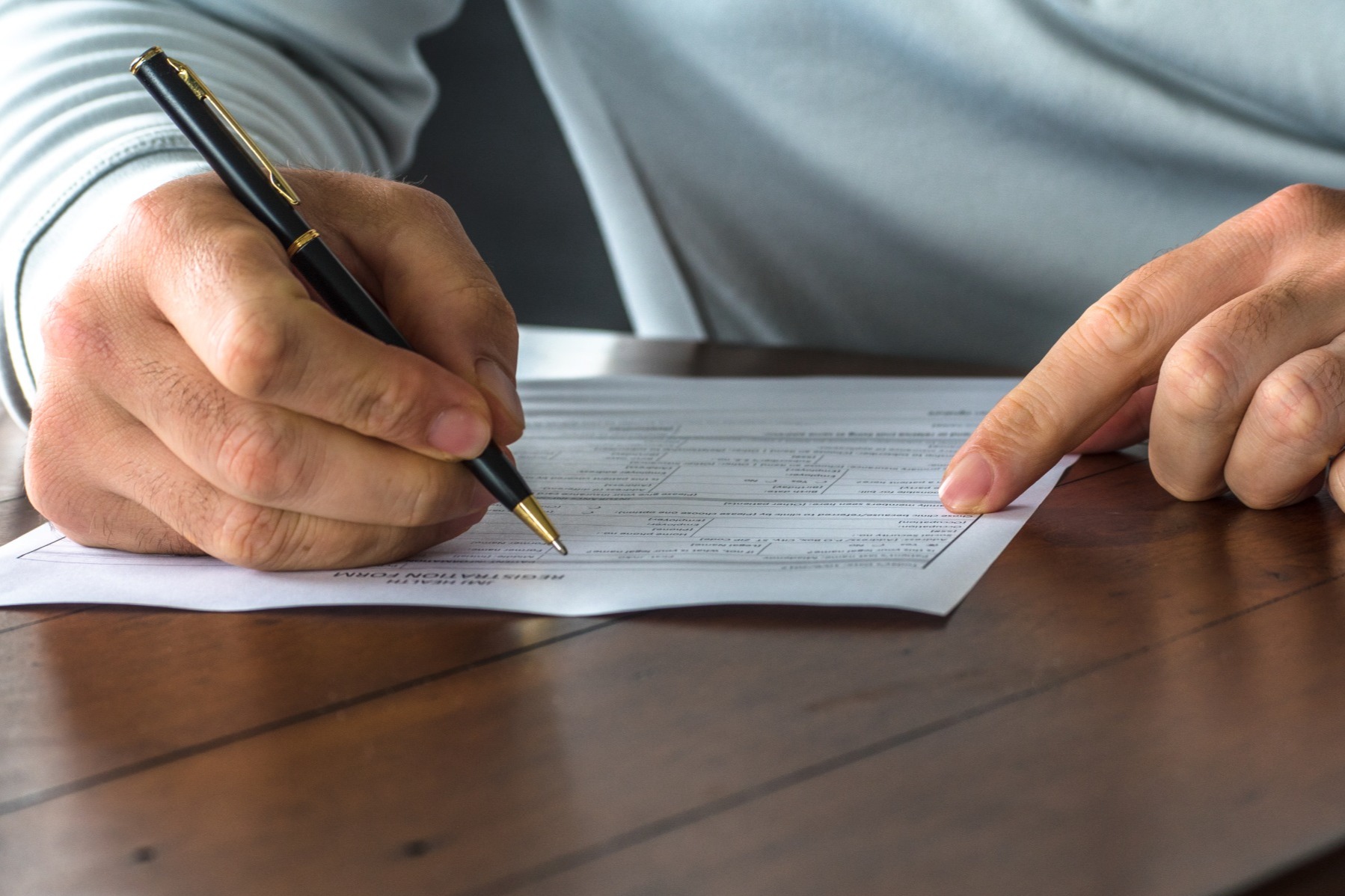 Close up view of a person's hands signing a document
