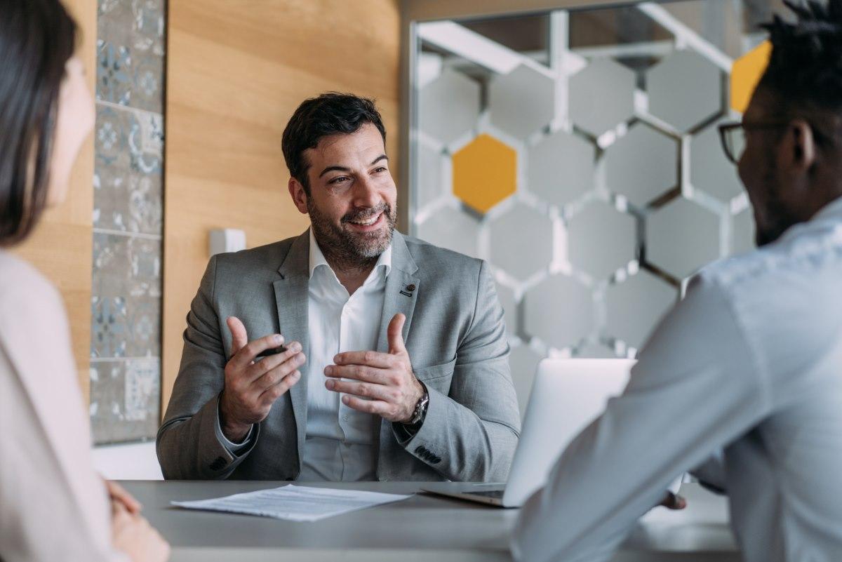Man sitting at table talking to two people