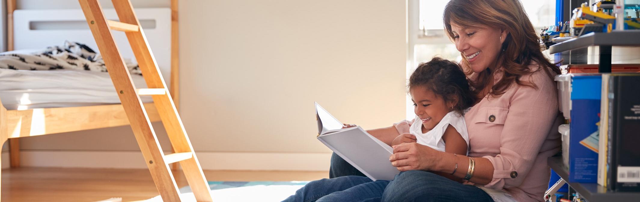 Woman reading to a young girl sitting in her lap